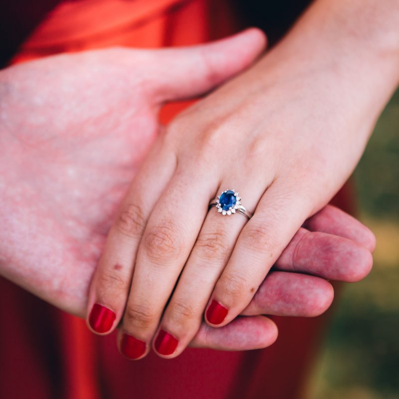 blue-sapphire-diamond-halo-engagement-ring-hands-holding